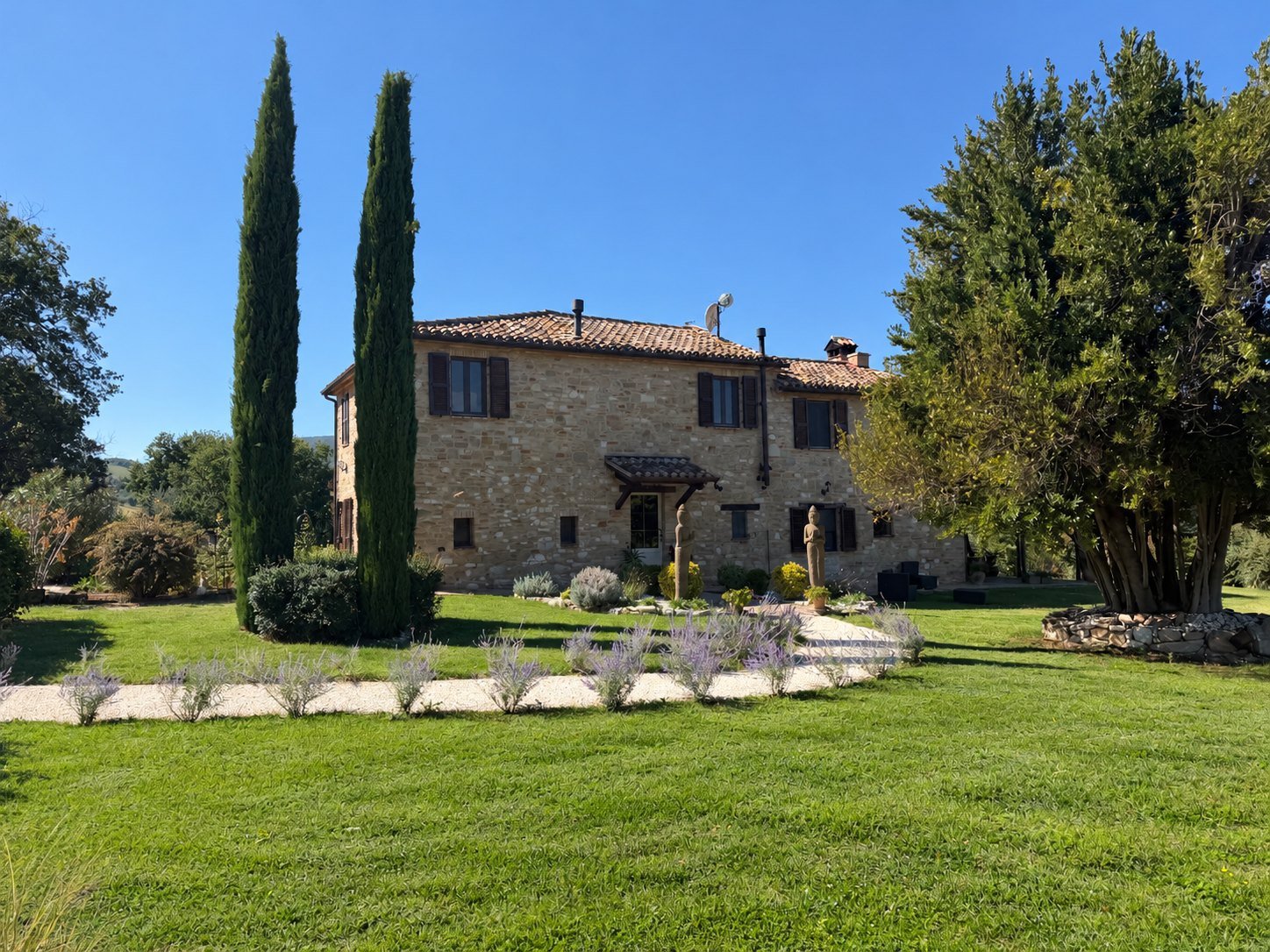 Casa Anandi, a restored stone farmhouse outside Treia in Le Marche, with cypresses and lavender in the garden